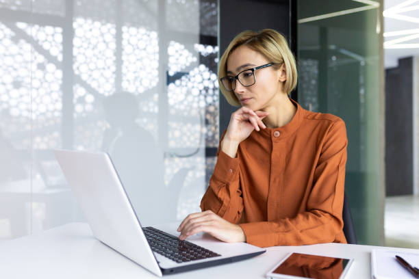istock Serious thinking woman working with laptop inside office at workplace, businesswoman solving technical task, female programmer coding new software 1596258259