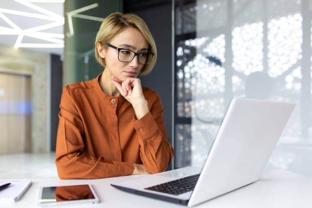 istock Serious thinking woman working with laptop inside office at workplace, businesswoman solving technical task, female programmer coding new software 1596264831