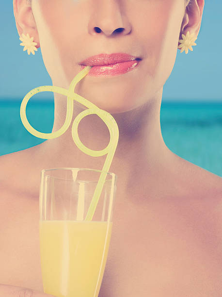 mujer joven vaso de jugo con rizado de paja - drinking straw drinking juice women fotografías e imágenes de stock