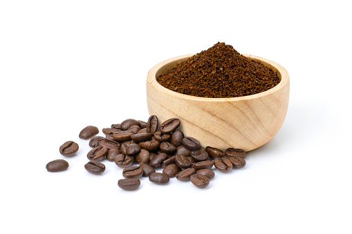 Roasted coffee beans with coffe powder (ground coffee) in wooden bowl isolated on white background.