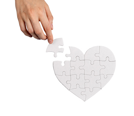 Completing heart shaped puzzle with missing lacking piece isolated on white background. Love problems solving concept.