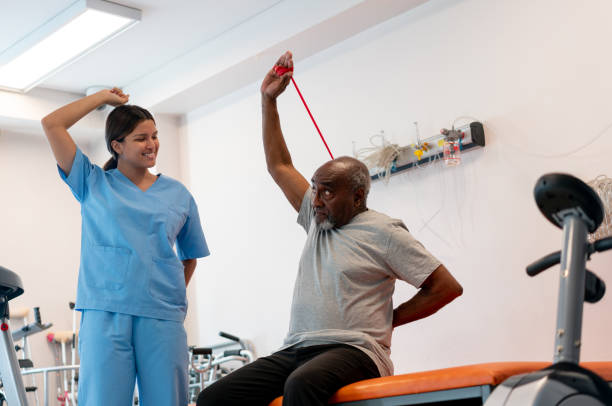 istock Female therapist guiding a senior patient's workout while he uses a resistance band at a physical recovery center 1596312628