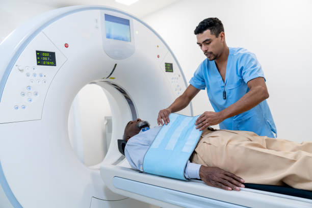 istock Male technician preparing a senior black patient on the CAT scan machine while explaining the procedure 1596313157