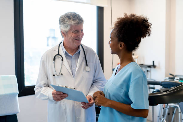 istock Caucasian orthopedist talking with black physiotherapist about a patient while looking at the medical chart in a physical recovery center 1596313185