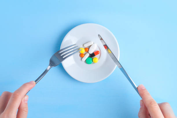 istock MMedicine concept, pills concept. Taking the medicine. Plate with multicolored tablets, capsules, medicine, fork and knife on a blue background 1596314243