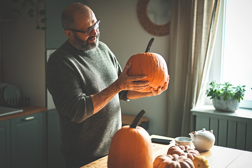 Mature adult man in the kitchen with pumpkin