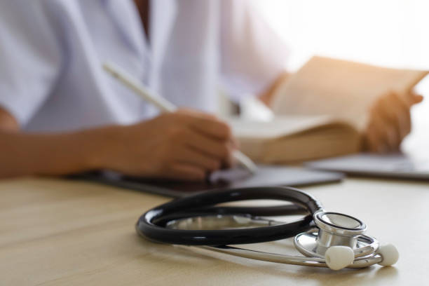 istock Doctor write on digital tablet computer and read book at office in clinic or hospital 1596322748