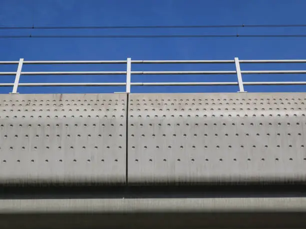 a concrete railroadbridge with a dot pattern against a blue sky