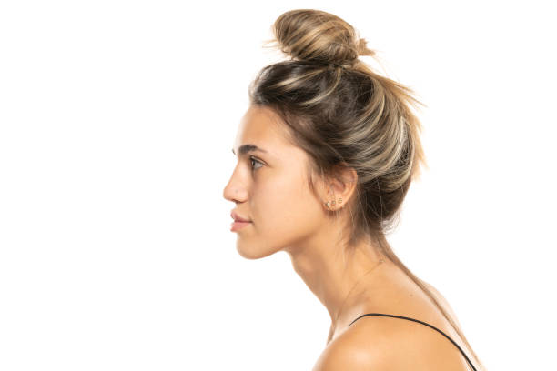istock woman with messy loose bun and no makeup on a white studio background. side profile view 1596436093