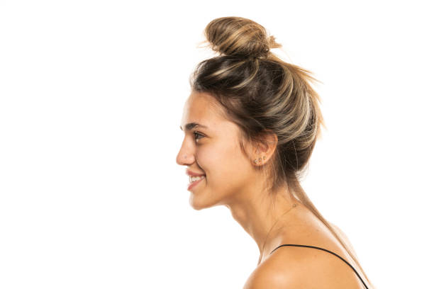 istock smiling woman with messy loose bun and no makeup on a white studio background. side profile view 1596436098