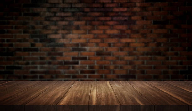 istock empty wood table with vintage brick wall background for product placement. brown wooden table at foreground in dark interior room. rustic wooden table with light at the middle. 1596449905