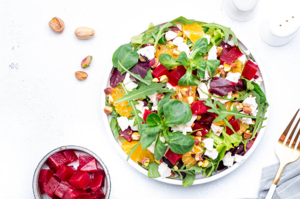 istock Beetroot and white cheese salad with arugula, lettuce,  orange and pistachios on white table. Fresh useful dish for healthy eating 1596461575