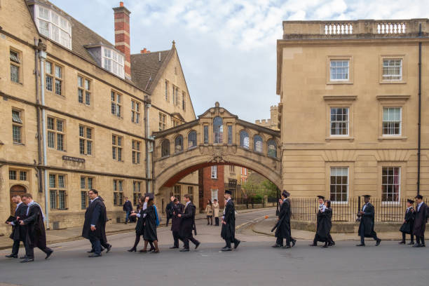 students passing hertford bridge, or bridge of sighs, on their way to their graduation ceremony, oxford university, uk - hertford college imagens e fotografias de stock