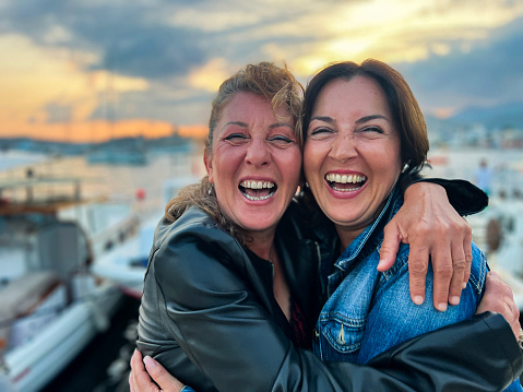 Mid age, happy best friend women holding each other lovely. Sunset time, in seaside and golden hours.