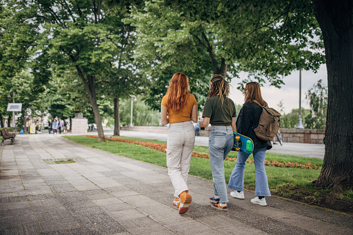Three people, young women friends taking a walk in city together.