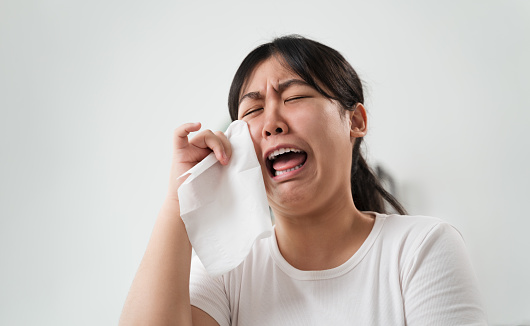 Portrait of a Sad Asian woman crying wipes her tears with a tissue paper towel.