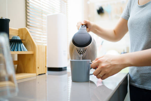 istock Woman boiling water in kettle. 1596653746