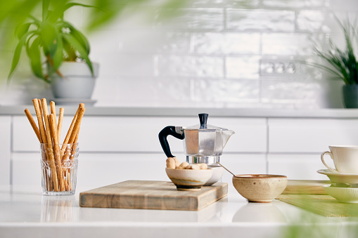 Morning coffee art serving, on a white kitchen table in a modern white kitchen filled with plants, image  with a free space for copy