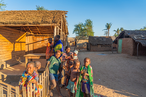 Morondava, Madagascar - May 31.2023: Malagasy family with them children at sunrise, background a wood hut