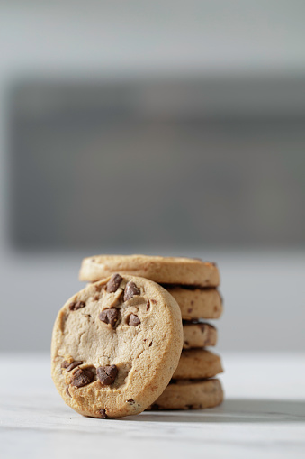 Christmas themes: close up view of unrecognizable mother and daughter preparing chocolate chips cookies in a baking sheet for Christmas holidays. High resolution 42Mp indoors digital capture taken with SONY A7rII and Zeiss Batis 40mm F2.0 CF lens