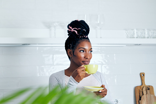 Portrait of a cute and relaxed young girl in the kitchen, early bird morning routine, drinking coffee, representing positive attitude and a healthy lifestyle, enjoying a single life, an image with a large copy space