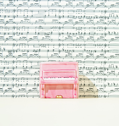 Pastel pink piano on the stage. Music scale background. Front view.