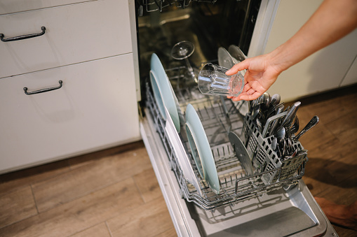 woman uses the dish washer machine at her home.