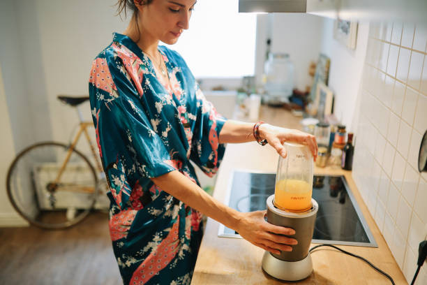 istock woman making a fruit smoothie in a blender at home 1596811274