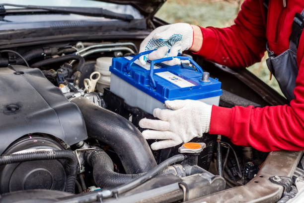 a car mechanic installs a battery in a car. battery replacement and repair - power supply power supply box power equipment imagens e fotografias de stock