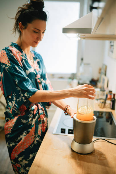 istock woman making a fruit smoothie in a blender at home 1596824817