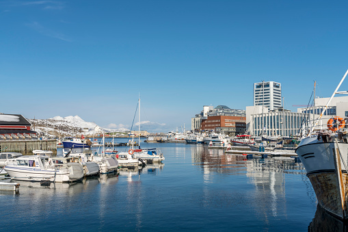 Northern town of Bodo, harbor with deep blue sea and fishing boats on sunny day. Clear blue sky.