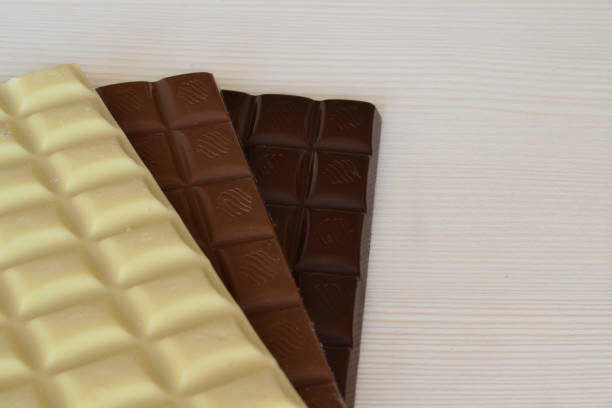 istock three bars of chocolate lie on a white wooden table 1596876232