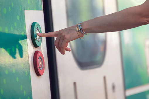 A woman pushing a button of a train door to enter.