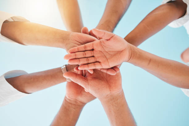 istock Circle, low angle and team with hands together for collaboration, unity or support by a blue sky. Teamwork, diversity and group of people in an outdoor huddle for motivation, solidarity or community. 1596901154