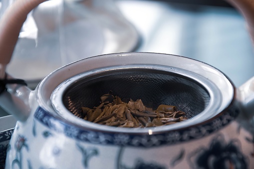 This evocative image showcases a moment of sensory delight as a beautifully crafted teapot shares space with a scatter of dried tea leaves on a kitchen table.