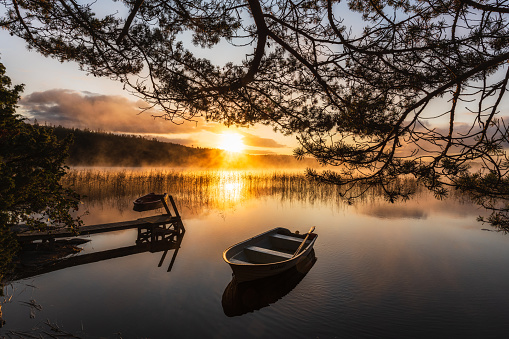 Row boat on calm lake at sunrise