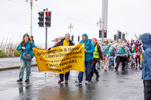 Multi-ethnic group of female activist protesting for women's rights on city streets while men are standing in the background.