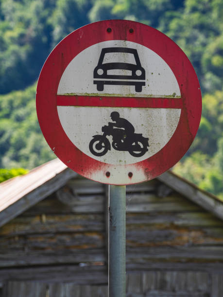 Circular red warning sign on old road prohibiting driving.