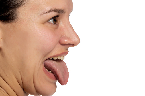 Profile woman portrait sticking the tongue out on a white studio background