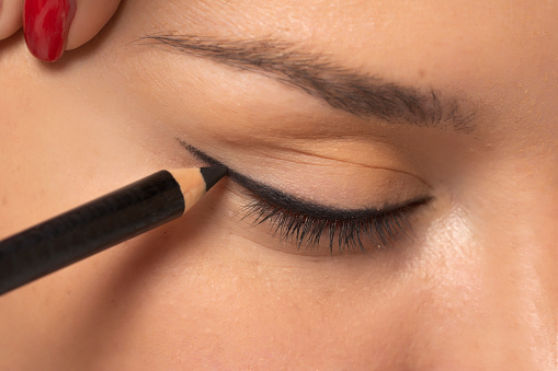 woman applying cosmetic pencil on the eye.
