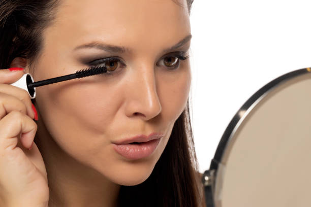 istock beautiful woman applying mascara on a white background 1596918543