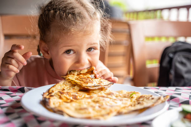 Little girl eating potato and cheese gozleme on wooden table. Traditional stuffed pancakes in Alanya, Turkey Little girl eating potato and cheese gozleme on wooden table. Traditional stuffed pancakes in Alanya, Turkey. High quality photo young hot stock pictures, royalty-free photos & images