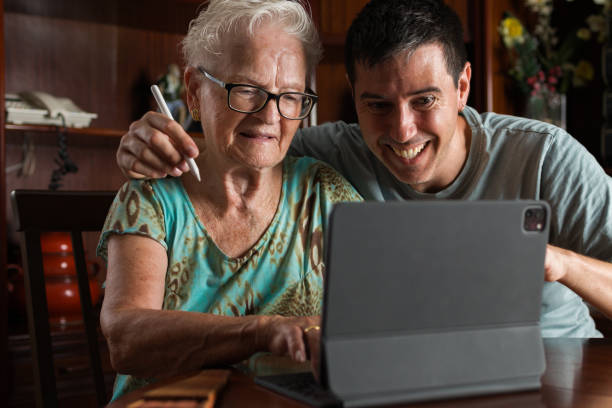 istock active grandmother and grandson smiling together while using a laptop computer digital tablet to create digital art and drawing.creative elderly woman and technology at home.family love concept. 1596935627