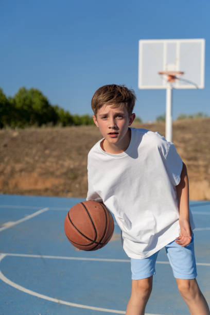 istock Young boy playing basketball outdoors. 1596972371