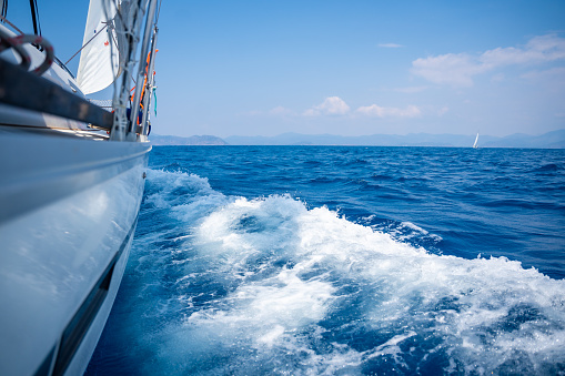 Yacht sailing in an open sea. Close-up view of side of the boat. Clear sky after the rain, waves and water splashes. High quality photo