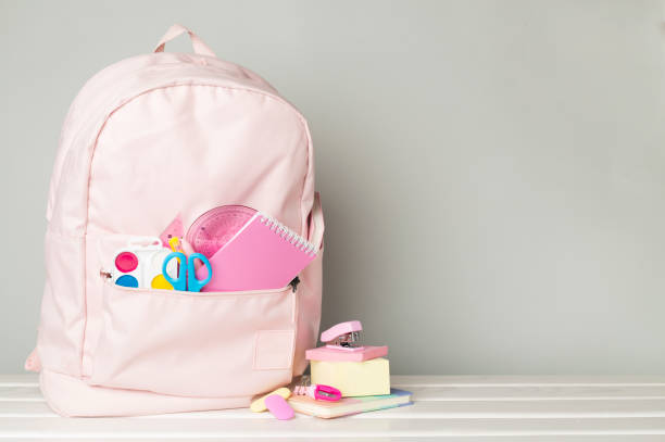 istock Pink school backpack with stationery on wooden table 1596975273