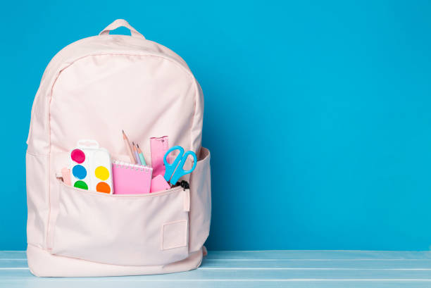 istock Pink school backpack with stationery on wooden table 1596975276