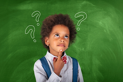 Child thinking with question mark on blackboard
