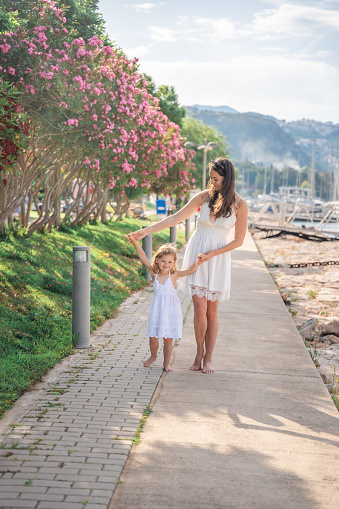 Happy mother and daughter child having fun on luxury yachts on background in marina. Family travel, lifestyle, vacation concept. High quality photo