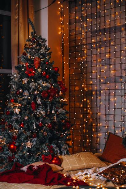 istock Christmas tree decorated with a golden garlands light and cozy beds with pillows. 1597025322